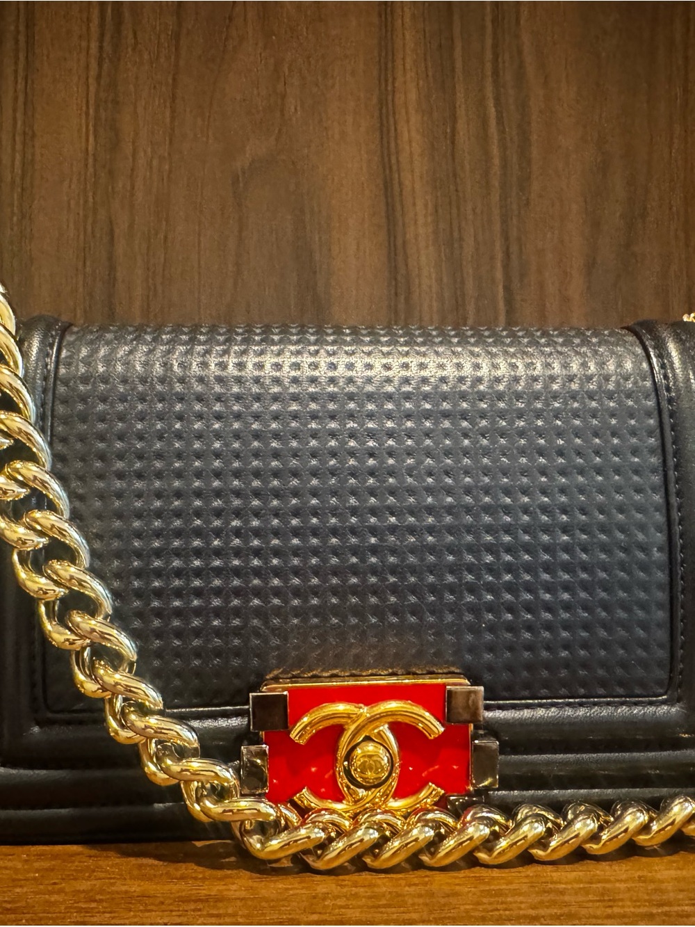 CHANEL Black Quilted Shoulder Bag with Gold Chain and Red Logo Accent